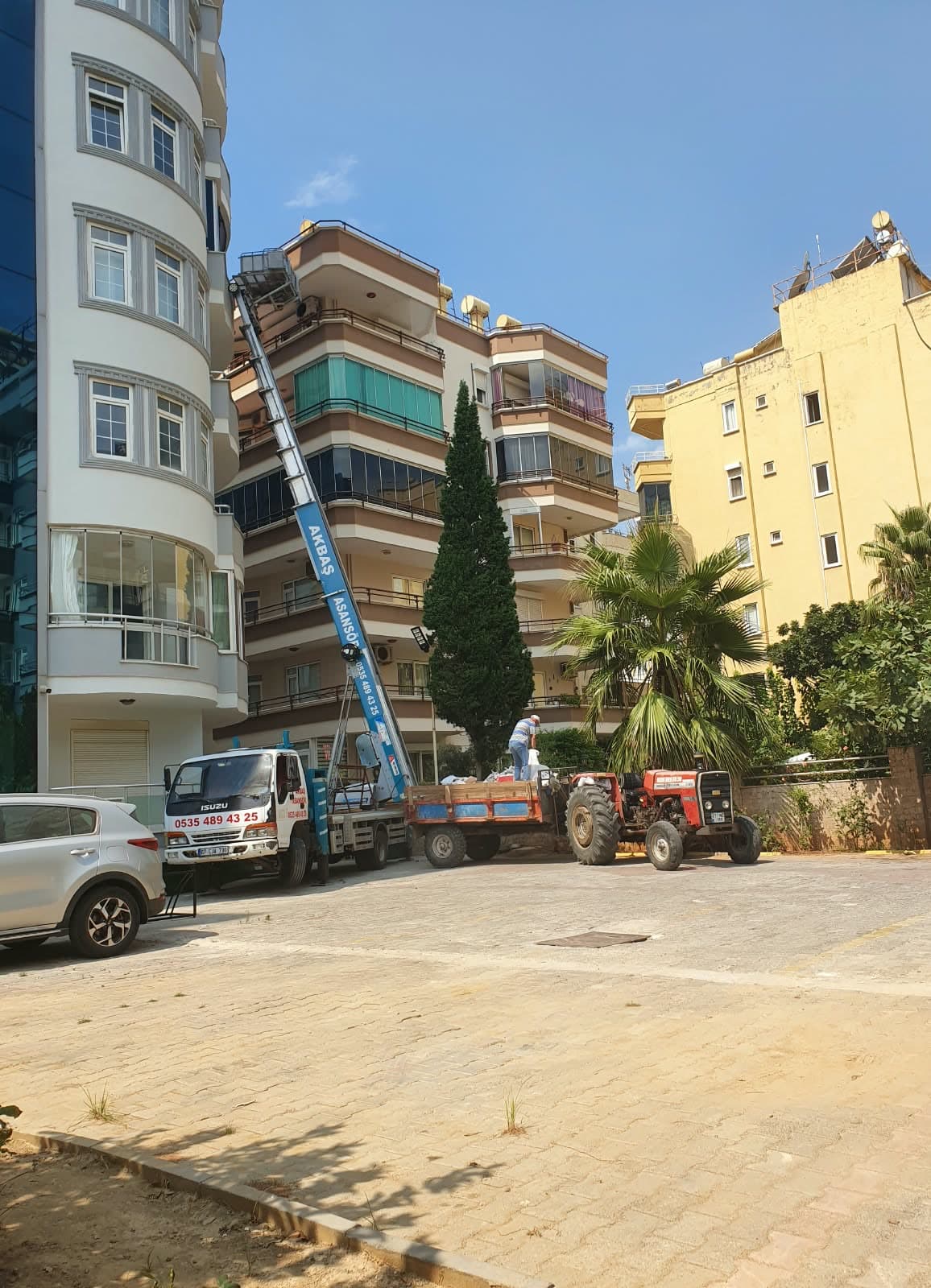 Alanya'da bir apartmana kurulmuş Akbaş dış cephe asansörü; ekip eşyaları araca yüklüyor