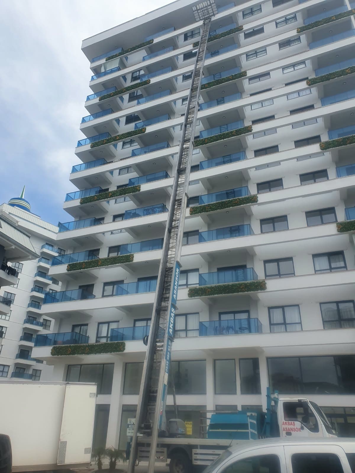 Alanya'da yüksek bir apartman bloğunun cephesi boyunca uzanan Akbaş nakliyat asansörü